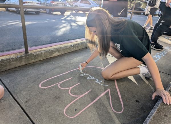 Immersed in her work, Katie Thiel ‘25 works on her chalk message for deaf awareness on the sidewalk. Her piece was one among many created during ASL Club’s Chalk Walk activity. 